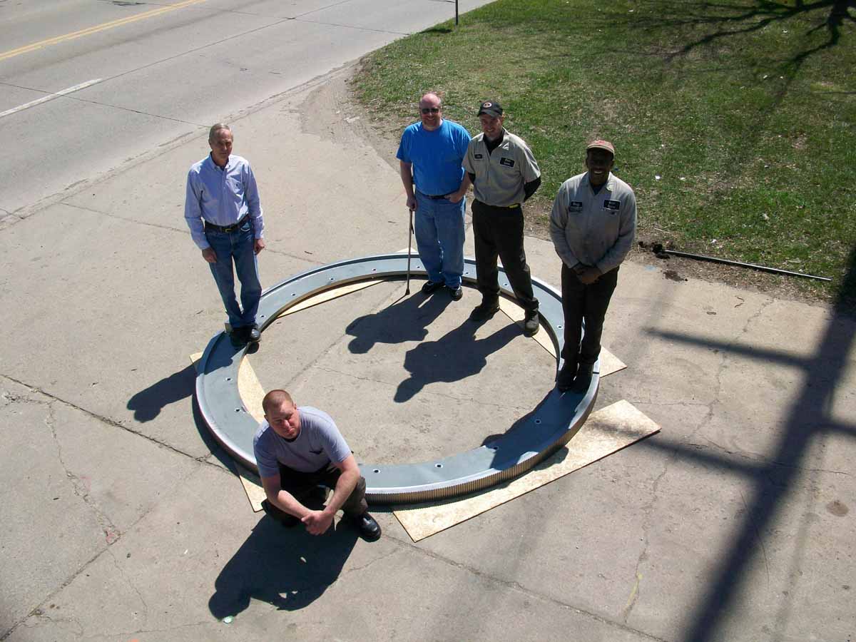 Three Men standing around a large custom bearing